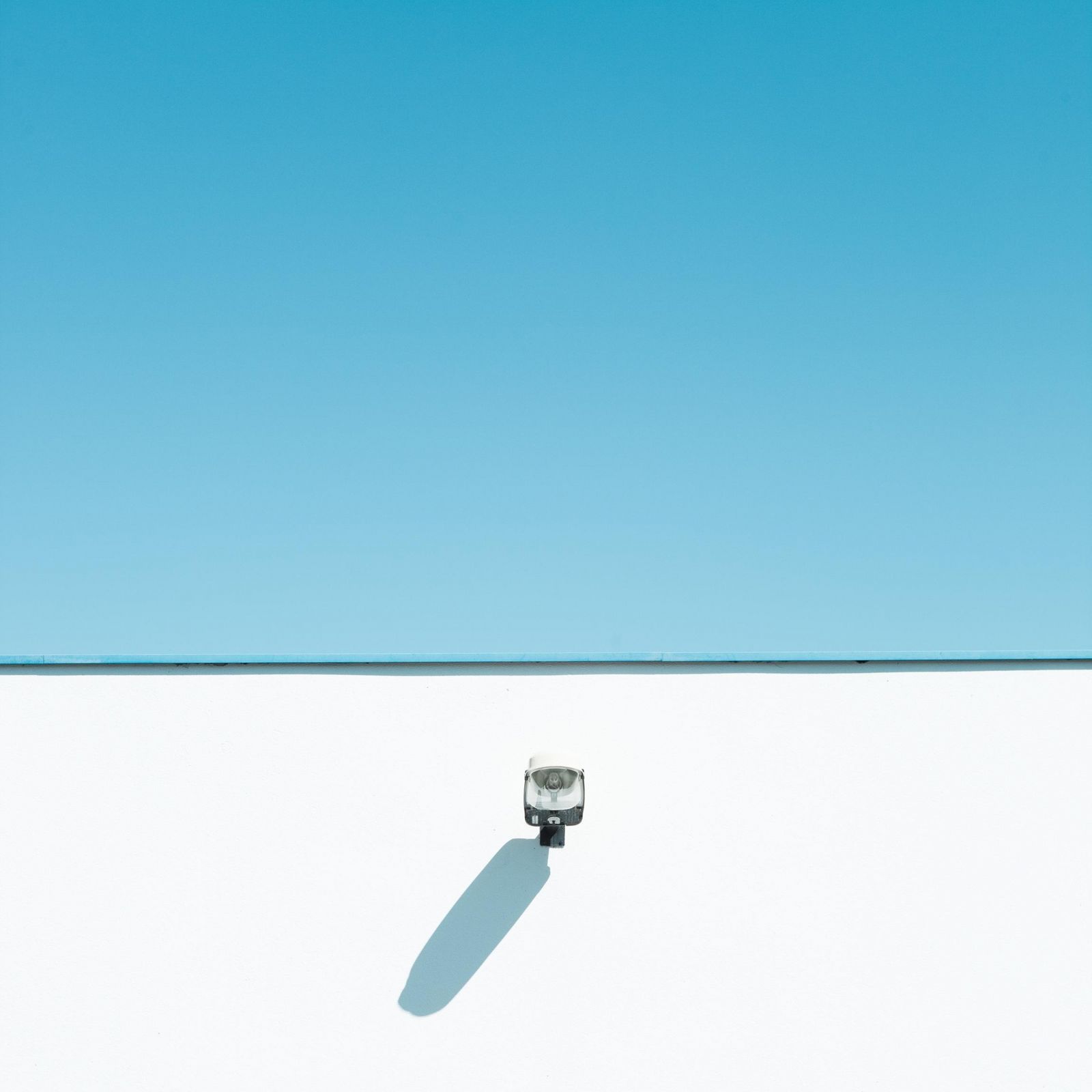 Sample image of a security camera on a white wall under a blue sky